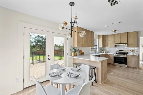 a open dining room with stainless steel appliances granite countertop furniture and a chandelier