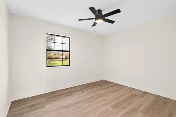 an empty room with a window and a ceiling fan
