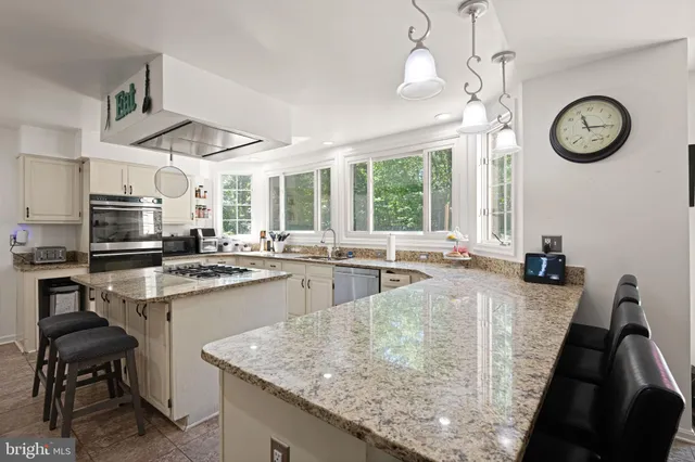 a kitchen with kitchen island granite countertop a sink a counter space appliances and cabinets