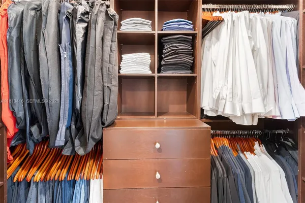 a view of walk in closet with clothes and shoes