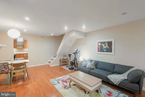 a living room with furniture and a dining table with wooden floor