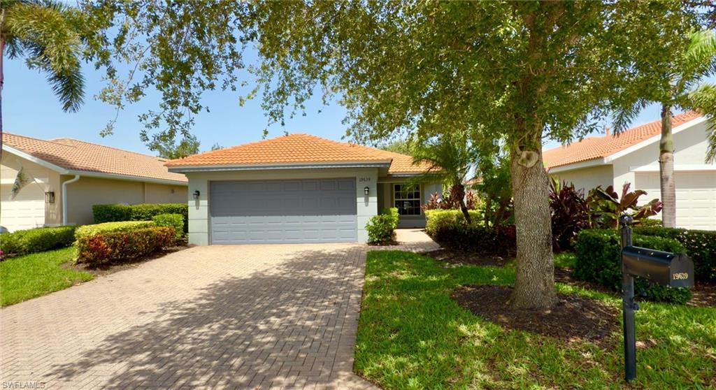 Ranch-style house with a tiled roof, decorative driveway, an attached garage, and stucco siding