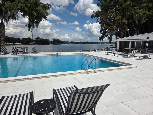a view of swimming pool with outdoor seating and lake view