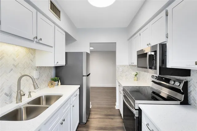 a kitchen with stainless steel appliances a sink a stove and a refrigerator with wooden floor