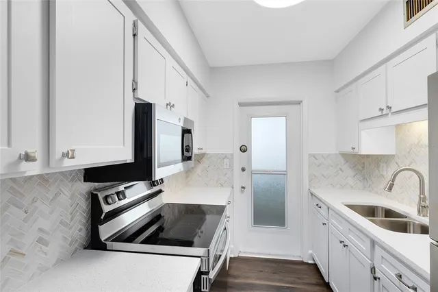 a kitchen with stainless steel appliances a sink a stove a microwave a counter top space and cabinets