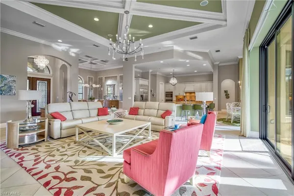 a view of a dining room and livingroom with furniture wooden floor a rug a flat screen tv a rug and a chandelier