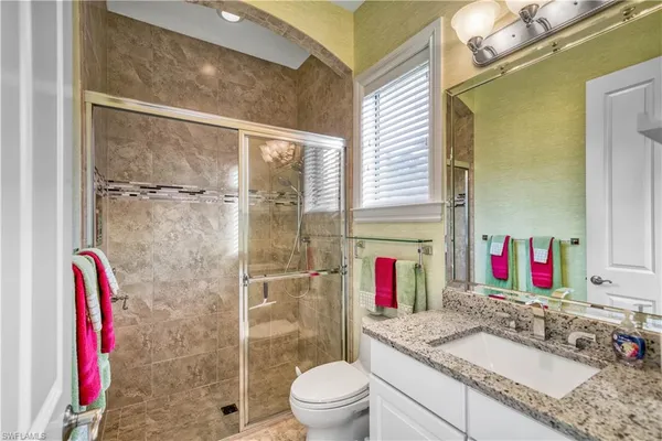 a bathroom with a granite countertop shower sink and toilet
