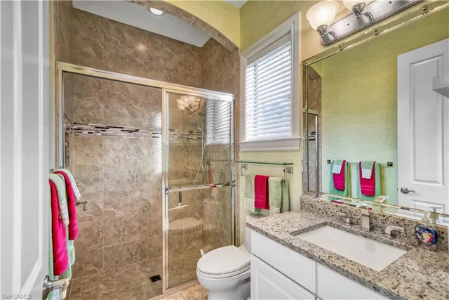 a bathroom with a granite countertop shower sink and toilet