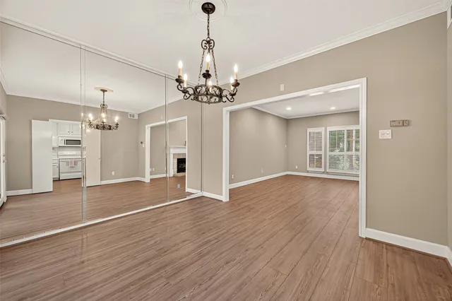 a view of an empty room with wooden floor and a kitchen