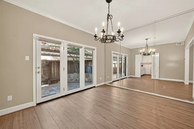 a view of an empty room with window and hardwood
