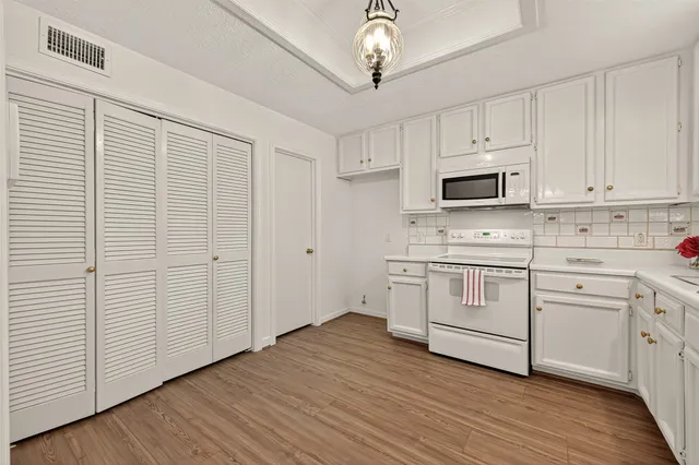 a kitchen with white cabinets stainless steel appliances and wooden floor