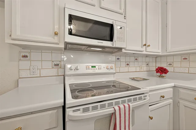 a kitchen with white cabinets and white appliances