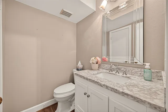 a bathroom with a granite countertop sink a toilet and a mirror