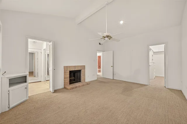an empty room with fireplace and chandelier fan