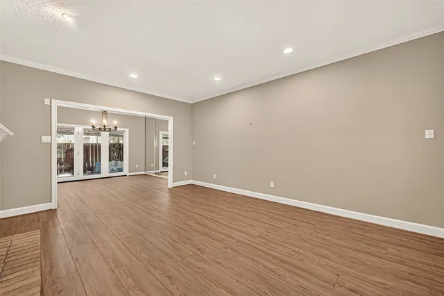 a view of an empty room with wooden floor and kitchen