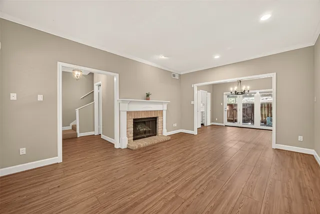 an empty room with wooden floor fireplace and windows