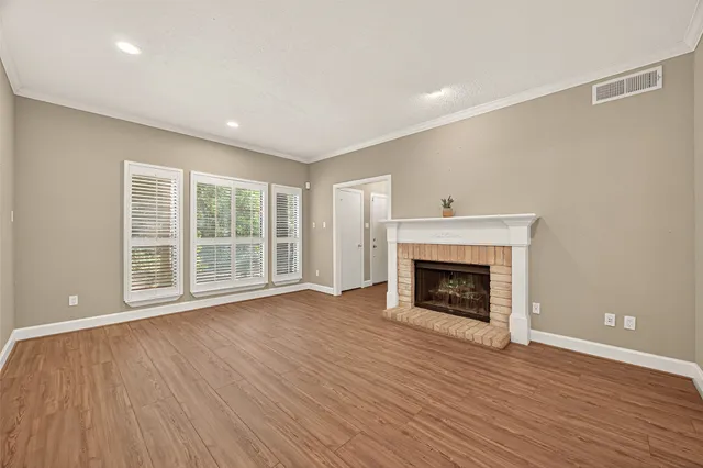 a view of an empty room with wooden floor fireplace and a window