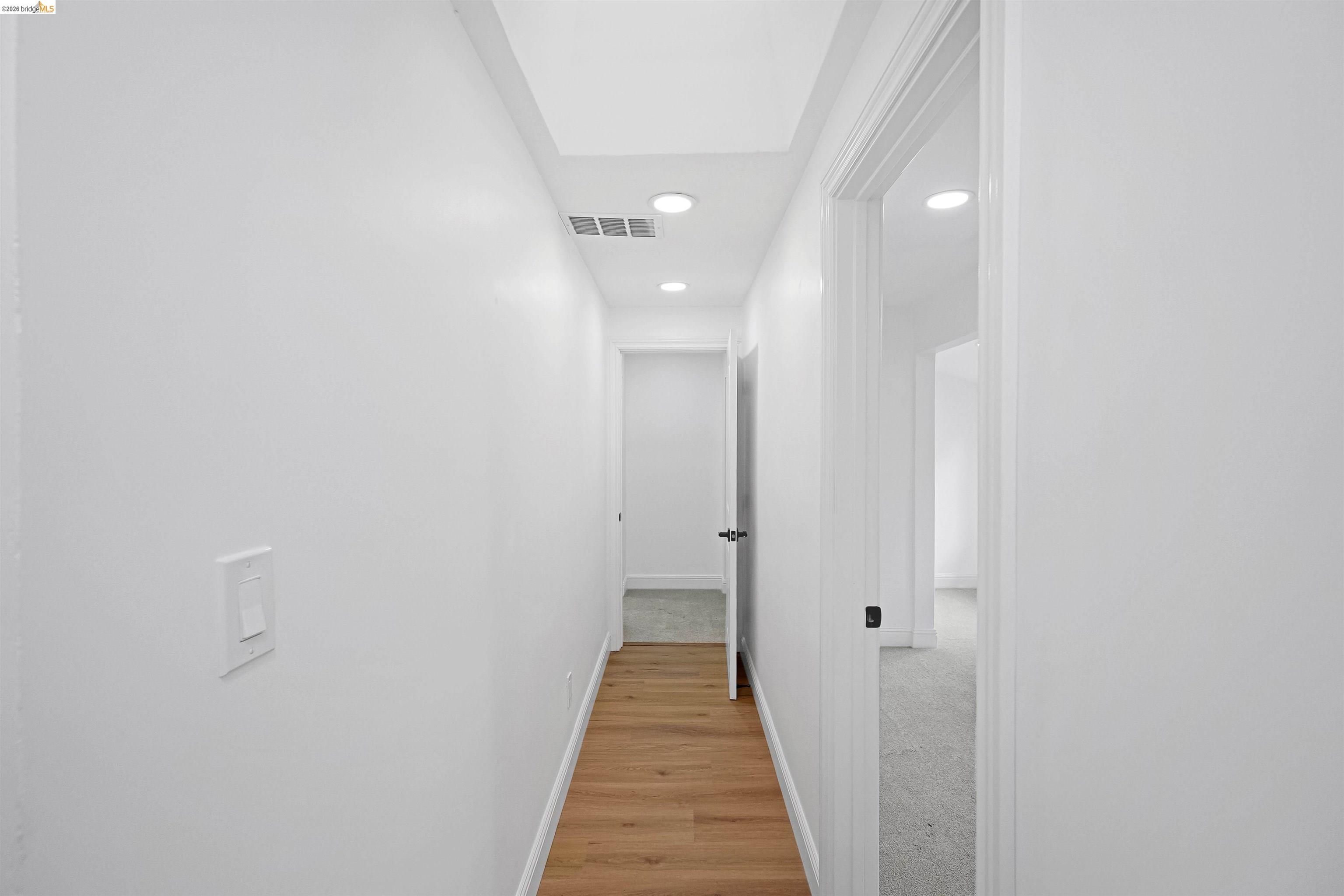 1812 Woolsey Street Berkeley, CA 94703 - Photo 23 of 48 Interior hallway featuring wood-finish flooring, white walls, recessed ceiling lighting, and multiple doorways