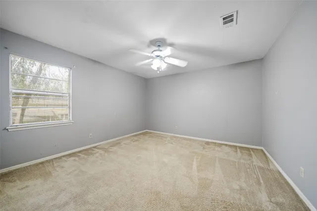 an empty room with a window and a ceiling fan