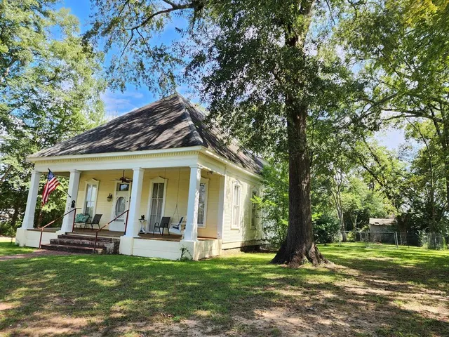 a view of a house with a big yard and large trees