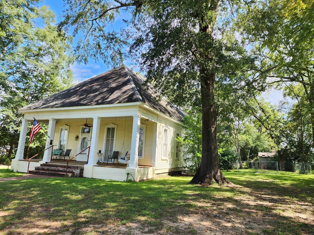 a view of a house with a big yard and large trees