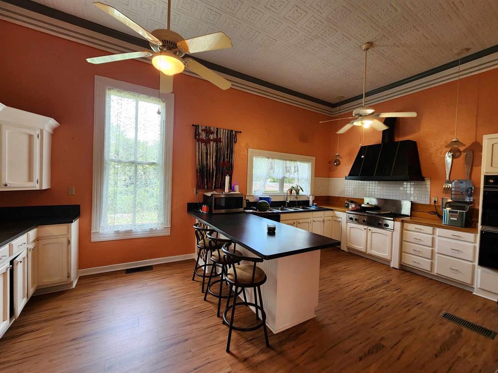 205 South 2nd Street Logansport, LA 71049 - Photo 31 of 36 a kitchen with stainless steel appliances granite countertop a stove top oven a refrigerator a dining table and chairs with wooden floor