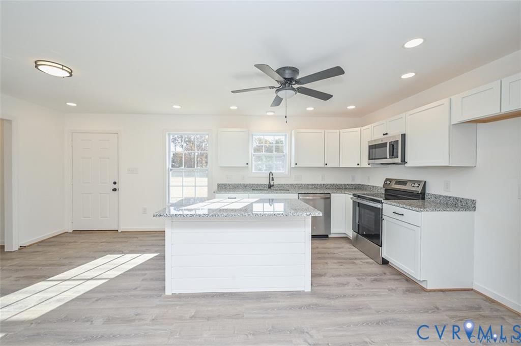 26471 Slash Pine Circle Ruther Glen, VA 22546 - Photo 7 of 36 a kitchen with stainless steel appliances granite countertop a stove top oven a sink a refrigerator white cabinets and wooden floor
