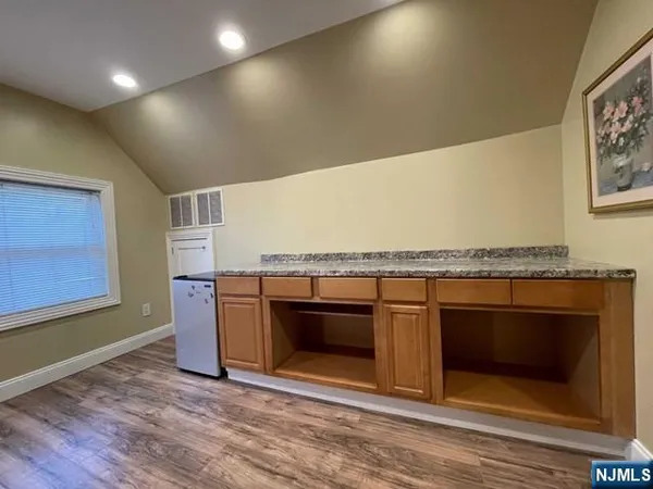 an empty room with wooden floor and kitchen view