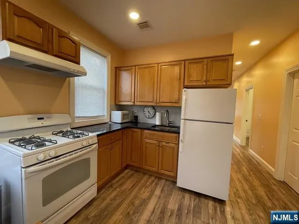 a kitchen with a stove a refrigerator and a wooden floor