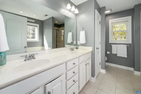 a spacious bathroom with double sink a mirror a vanity and a shower