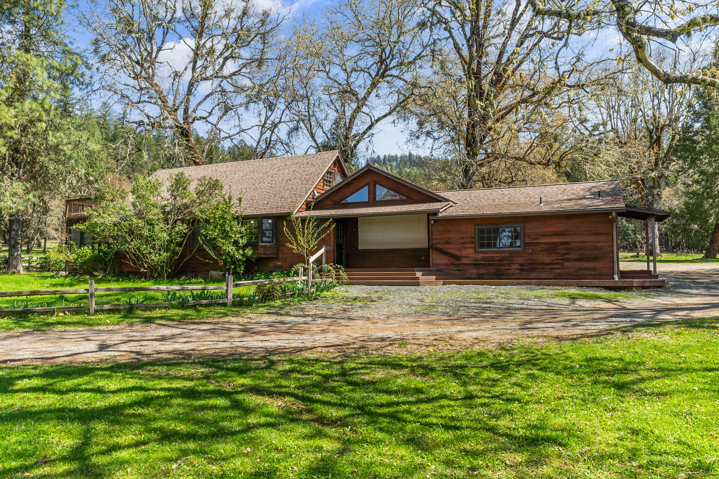 7589 Takilma Road Cave Junction, OR 97523 - Photo 9 of 54 a front view of a house with a garden and trees