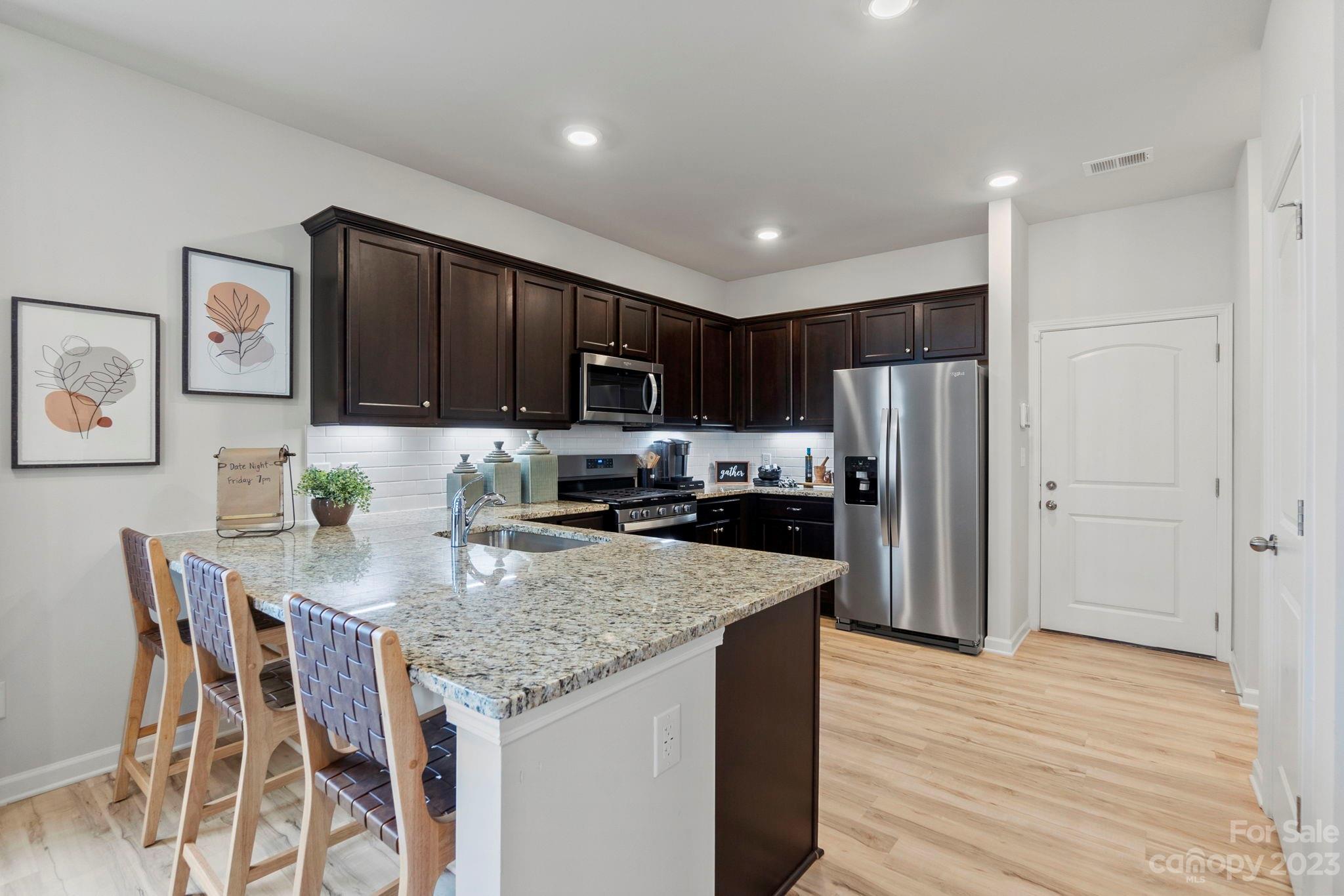 7856 Nelson Road Mint Hill, NC 28227 - Photo 7 of 30 a kitchen with stainless steel appliances granite countertop a refrigerator a stove top oven a sink dishwasher and wooden cabinets with wooden floor