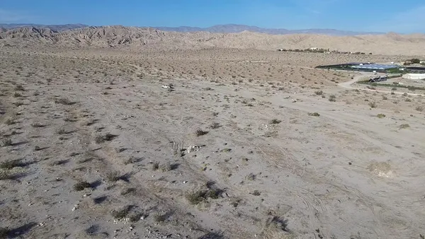 a view of a dry field with mountains in the background