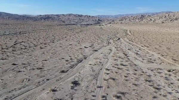 a view of a dry field with trees in the background
