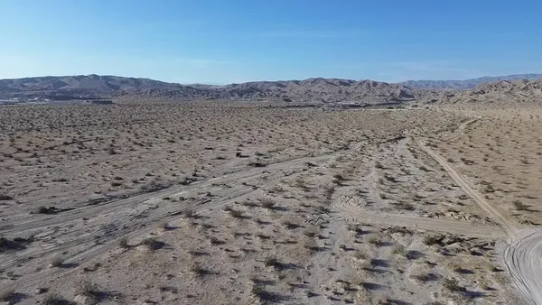 a view of a dry field with mountains in the background