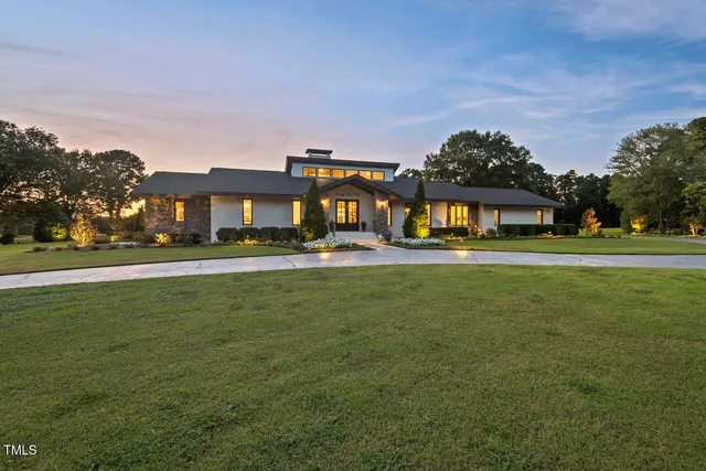 a front view of building with garden and trees
