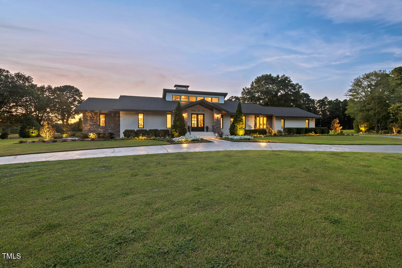 a front view of building with garden and trees