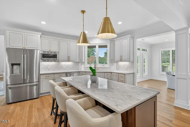 a kitchen with stainless steel appliances kitchen island granite countertop a table chairs sink and cabinets