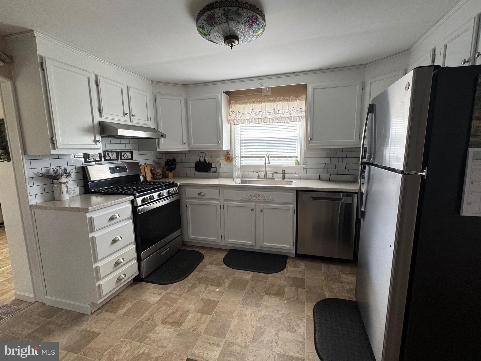 6101 Bethlehem Road Preston, MD 21655 - Photo 11 of 36 a kitchen with stainless steel appliances a stove a sink a refrigerator a window and cabinets