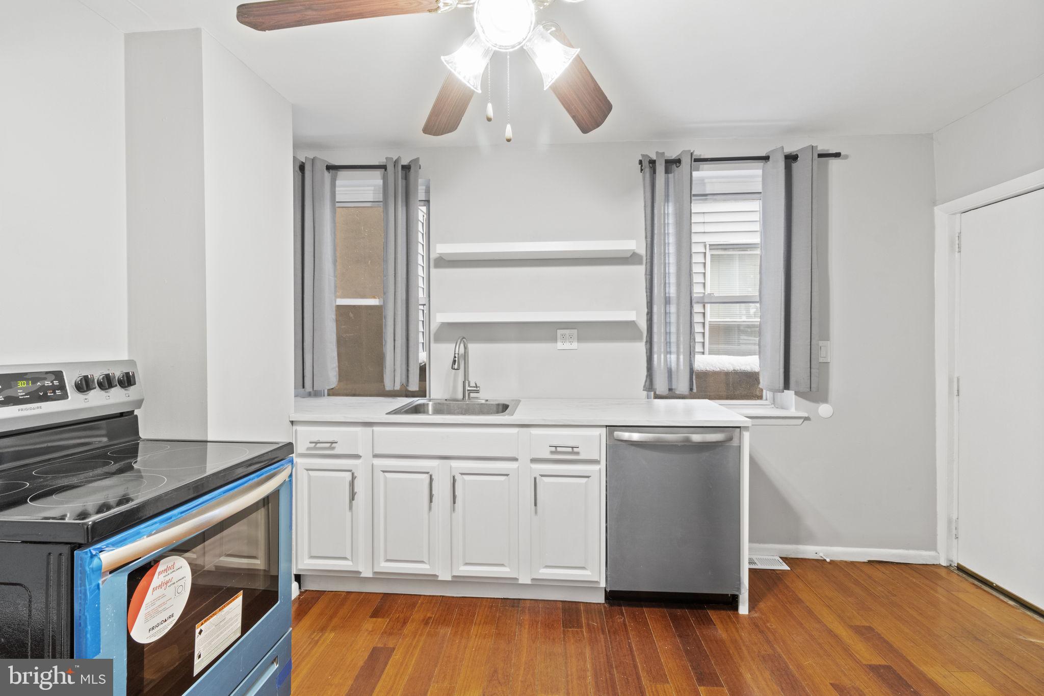 728 Christian Street, Unit 1 Philadelphia, PA 19147 - Photo 7 of 25 a kitchen with stainless steel appliances granite countertop a stove a sink and white cabinets with wooden floor