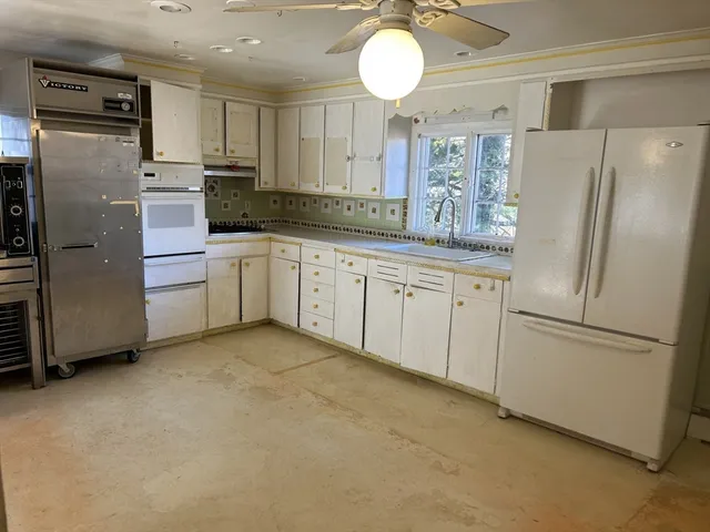 a kitchen with stainless steel appliances granite countertop a refrigerator a stove and white cabinets