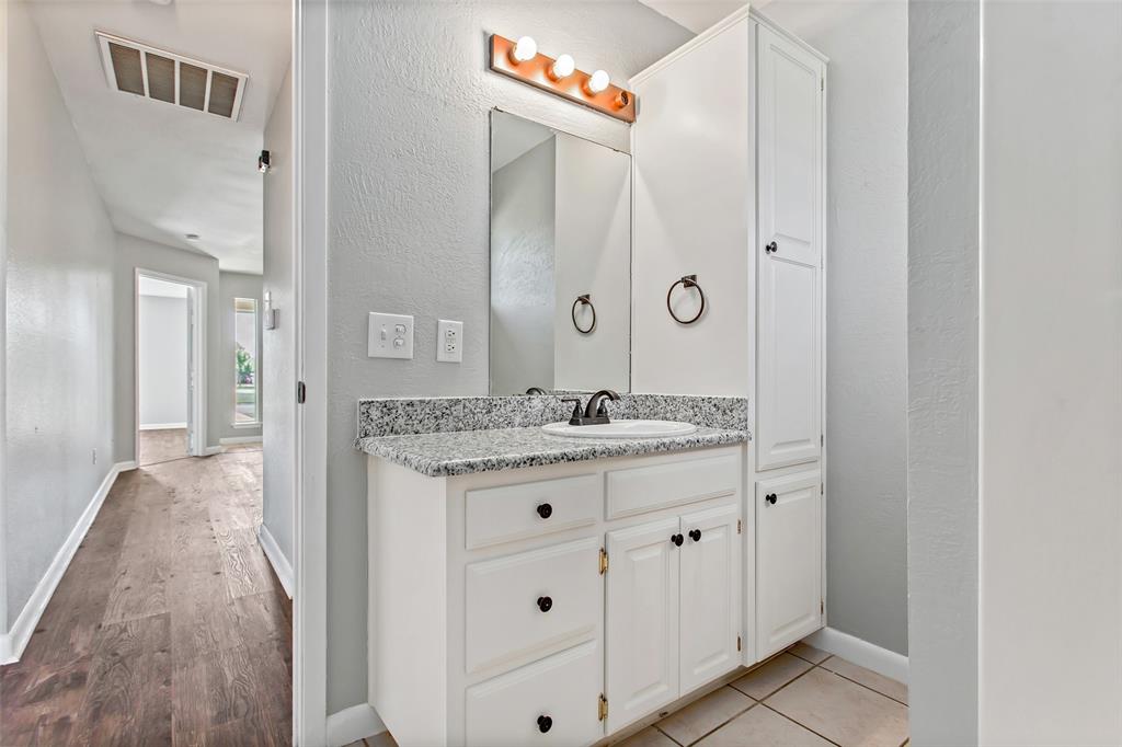 712 Billups Street Van Alstyne, TX 75495 - Photo 30 of 38 a bathroom with a granite countertop sink a mirror and a shower