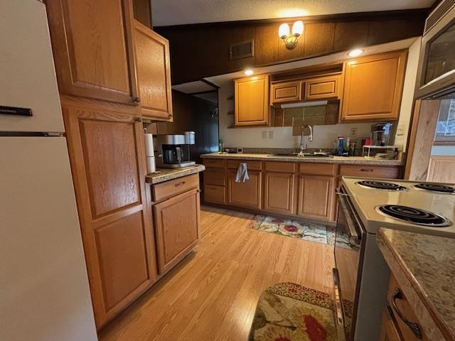 11452 Cooper Road Chisholm, MN 55719 - Photo 5 of 14 Kitchen with freestanding refrigerator, electric stove, light wood finished floors, and brown cabinetry