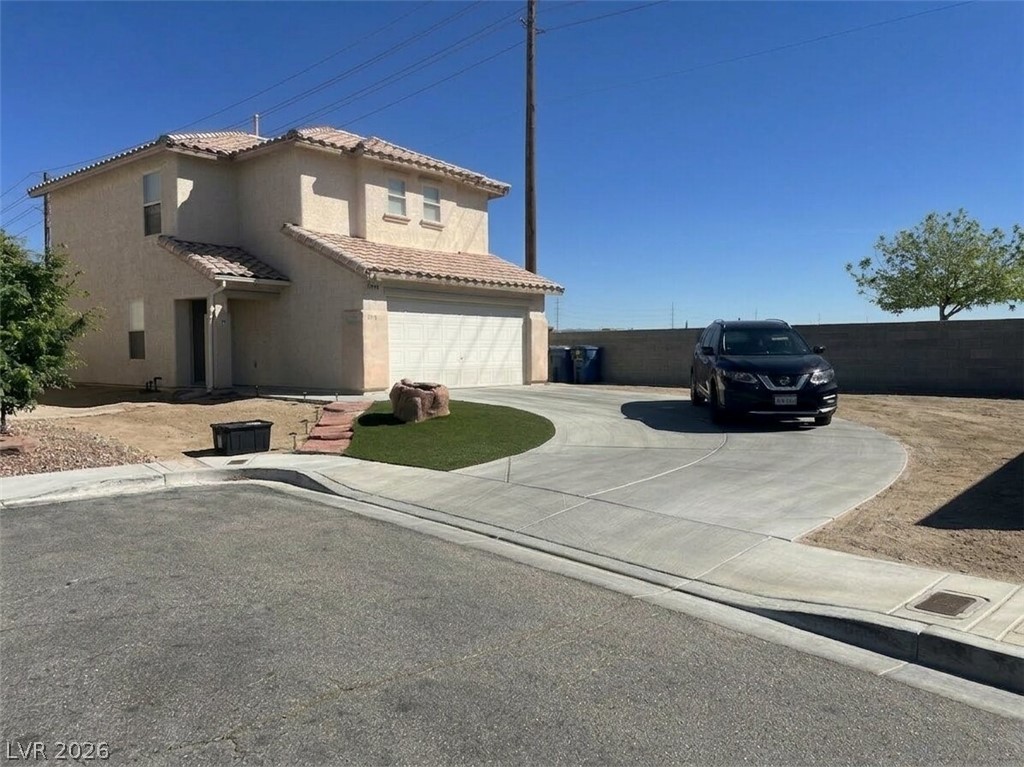 View of front facade featuring stucco siding, an attached garage, a tiled roof, and concrete driveway