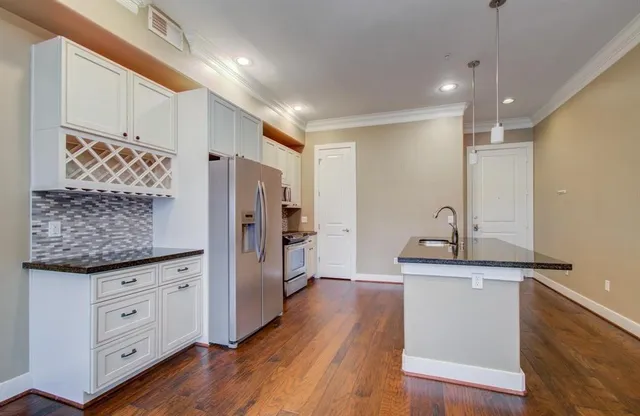 a view of cabinets with stainless steel appliances wooden floor and living room view