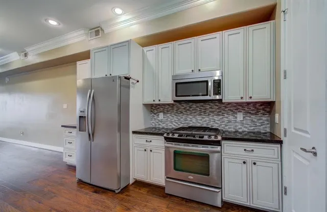 a kitchen with granite countertop white cabinets and stainless steel appliances
