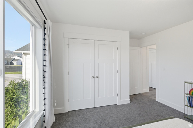 1422 West 3410th Street South Logan, UT 84321 - Photo 19 of 33 Bright interior space featuring a large window with white trim, gray carpet flooring, and white interior doors with panel detailing