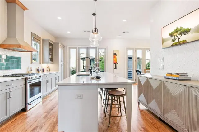 a kitchen with stainless steel appliances a stove a sink a kitchen island with wooden cabinets and floor