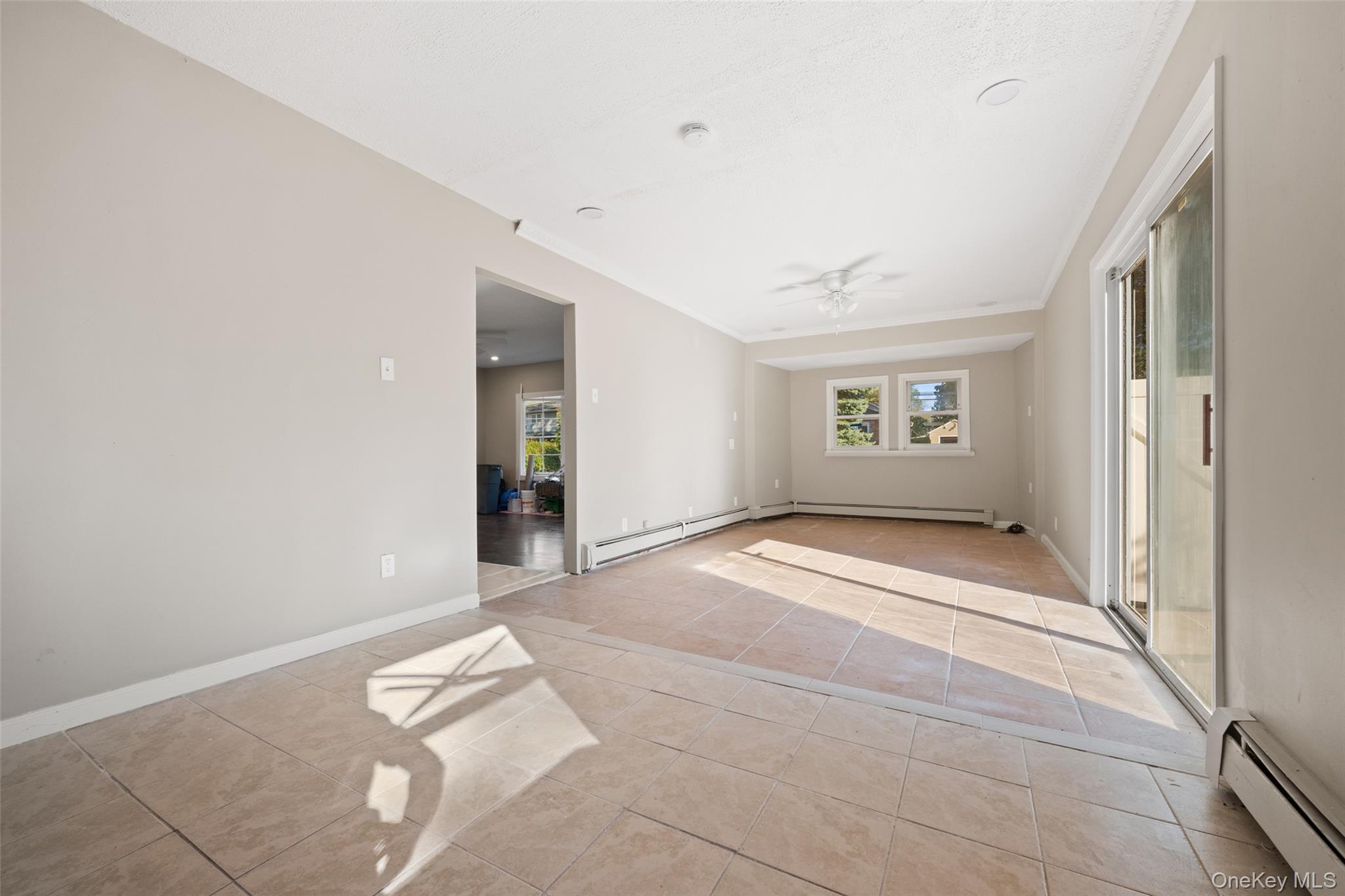 40 Duke Street Deer Park, NY 11729 - Photo 14 of 15 Unfurnished room featuring a baseboard heating unit, light tile patterned floors, a ceiling fan, and crown molding