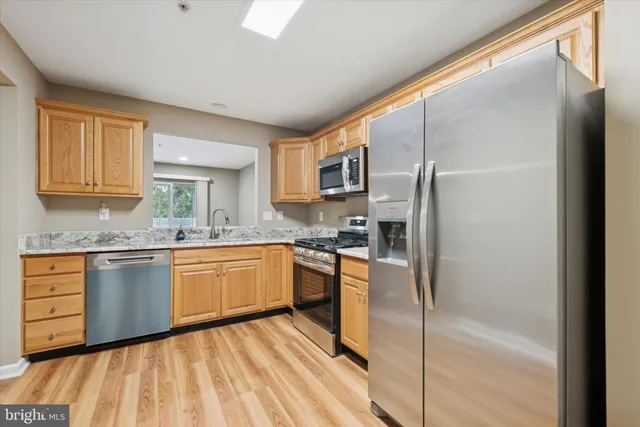 a kitchen with stainless steel appliances granite countertop a refrigerator a stove and a sink with cabinets